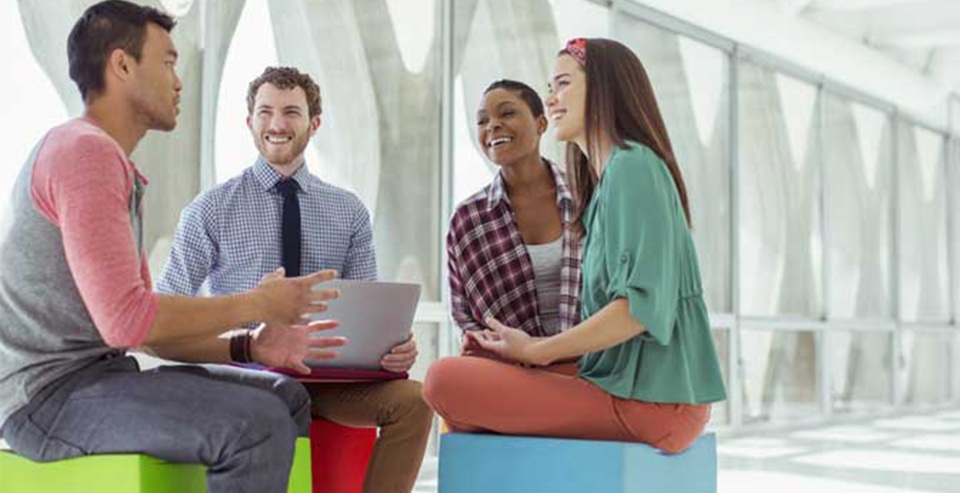 group of four people sitting in a circle talking and smiling