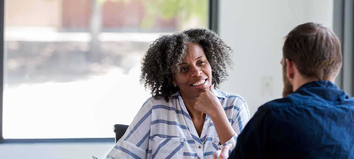 Person sitting across from person smiling with hand on chin